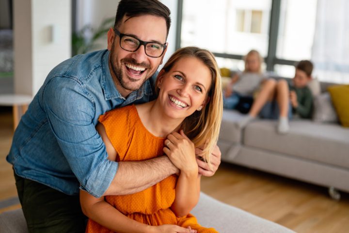 a happy couple with kids in background