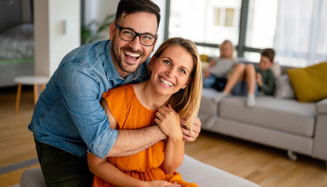 a happy couple with kids in background